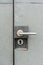 Scratch, dirty metal door handle lock on grey background