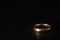 A scratched used old gold wedding ring on black background
