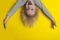 Screaming boy with blond long hair hanging upside down. Yellow background