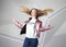 Screaming furious aggressive brunette woman with flying long hairs, flash studio portrait on modern wall