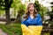 Screaming girl standing in Ukrainian flag worried about war. Young woman is feeling emotional pain after reading the