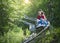 Screaming teen girl riding downhill on an outdoor roller coaster on a warm summer day.