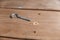 Screw with half-ring lies on the wood boards. C-hook screw anchor next to drill hole. Ceiling screw with cup ring for home,