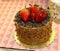 Scrumptous mini chocolate cake ornately decorated with icing and chocolate curls and glazed strawberries in bakery