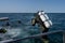 A scuba diver enters the water. Giant stride enter. Twin set tank. Ocean and blue sky in the background