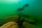 SCUBA diver exploring a cloudy inland lake with large boulders