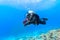 Scuba diver floating over coral reef.