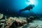 scuba diver over the wooden wreck of a diving boat with tank