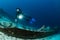 scuba diver over the wooden wreck of a diving boat with tanks