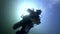 Scuba diver silhouette flashlight on background reflection sunlight underwater.