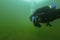 SCUBA diver swimming though fresh water weeds