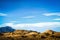 Sculpted sand dunes and hills in New Mexico with Blue mountains in distance against pretty blue sky with scattered clouds