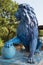 Sculpture of a blue lion with a blue ball against a green background