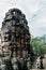 A sculpture carved from a rustic rock in the form of faces on four of its parts on the roofs of the ruins of the Bayon temple in