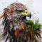 Sculpture and painting street art of eagle head full of colorful colors and covered with leaves and grass. on the old wall. Bird.