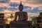 The sculpture of a sitting Buddha against a cloud sunset. Sukhotai