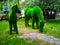 Sculpture of two horses from artificial grass on the background of trees.
