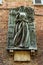 Sculpture of woman Contrada dell `Aquila on wall in medieval narrow street Casato di Sotto in Siena, Tuscany, Italy