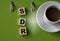 SDR - acronym on wooden cubes against the background of a green folder and a cup of coffee
