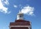Se up of a Top of lighthouse tower with a round white metal roof and arrow under blue caribbean sky. Lighthouse tower containing