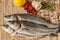 Sea bass fish with garlic, rosemary, tomatos and lemon on a wood table from above