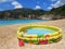 Sea blue waves and inflatable pool for kids in summer on the beach. Vacation and travel.