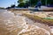 Sea is breaking foamy waves on the sandy, pebbles beach