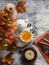 Sea buckthorn tea, maple leaves, fluffy carpet, books, pumpkin - cozy still life home interior on a gray background, top view