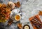Sea buckthorn tea, maple leaves, fluffy carpet, books, pumpkin - cozy still life home interior on a gray background, top view
