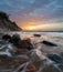 Sea cliff and beach lit by the setting sun