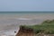 Sea cliffs of boulder clay in front of beaches. Clay Cliffs and Beach with Blue Sky and Water. Precipice coast near the sea.