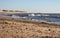 Sea coast with beach full of pebbles. Seashore with surf waves. Empty sand beach. Dramatic coastline.