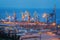 Sea commercial port at night in Mariupol, Ukraine. Industrial view. Cargo freight ship with working cranes bridge in sea port