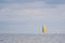 On the sea floats a sailboat with a bright yellow sail and the sky is full of clouds