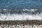 The sea foamy waves on an empty pebble beach