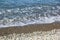 The sea foamy waves on an empty pebble beach