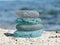 Sea glass pyramid on beach sand with blurred seascape background. Beachcombing, beach walk. Harmony and balance concept