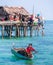 Sea Gypsy family on their sampan near their huts on stilts