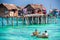 Sea Gypsy family on their sampan near their huts on stilts