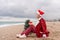 Sea Lady in Santa hat plaid shirt with a red mug in her hands enjoys beach with Christmas tree. Coastal area. Christmas