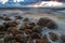 A sea landscape with rocks, a storm and a setting sun. Waves, rocks, storm and clouds.n