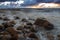 A sea landscape with rocks, a storm and a setting sun. Waves, rocks, storm and clouds.n