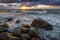 A sea landscape with rocks, a storm and a setting sun. Waves, rocks, storm and clouds.n
