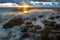 A sea landscape with rocks, a storm and a setting sun. Waves, rocks, storm and clouds.n