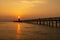 Sea landscape. Sunrise at the old red lighthouse of Lignano with a shelter, wooden quay.