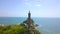 Sea light house on rocky island in blue water aerial landscape. Drone view lighthouse tower on green island in ocean.