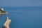 Sea, lighthouse and the floating boat on a summer day.