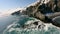 Sea lions lie on large rock rookery among blue sea water