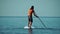 Sea man sup. Asian athlete man swimming in sea and paddleboarding at summer sunset. Healthy strong male enjoy outdoor