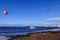 Sea with people parachuting over it in the bright skyline